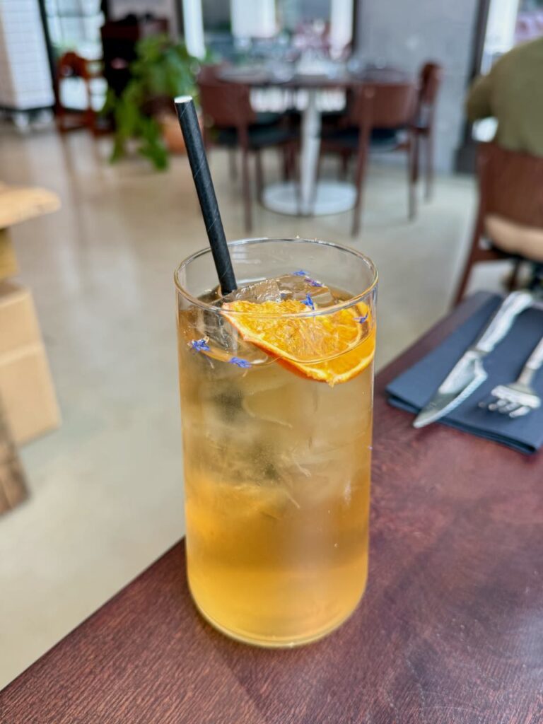 Thé glacé avec une orange séchée et des fleurs bleues dans un grand verre transparent