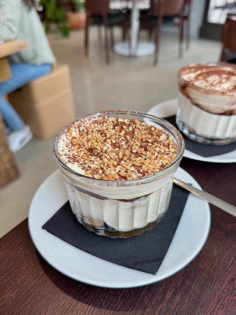 Un tiramisu saupoudré d'éclats de pistache dans un verre transparent
