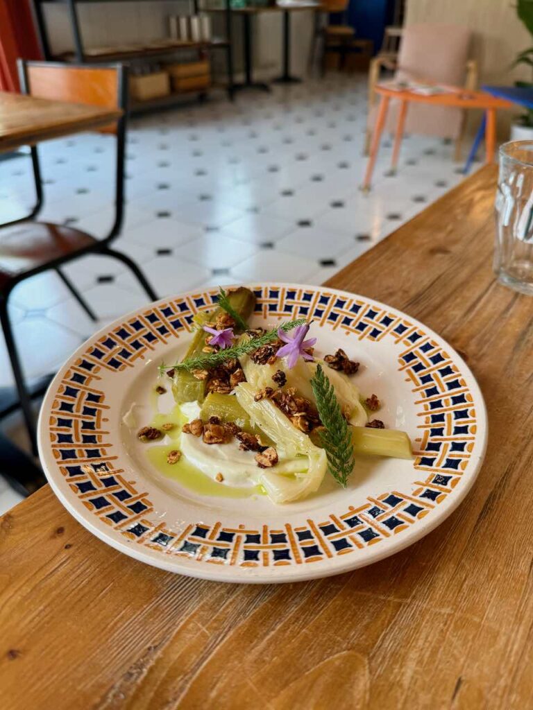 Poireaux vinaigrette, tagètes, fleurs et cacahuètes dans une asiette blanche creuse
