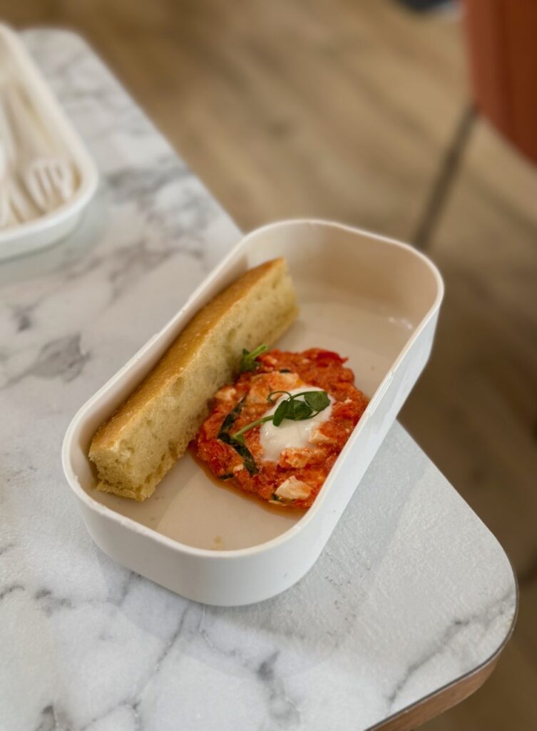 Mezze grec et tranche de focaccia dans un bento blanc rectangulaire sur une table effet marbre