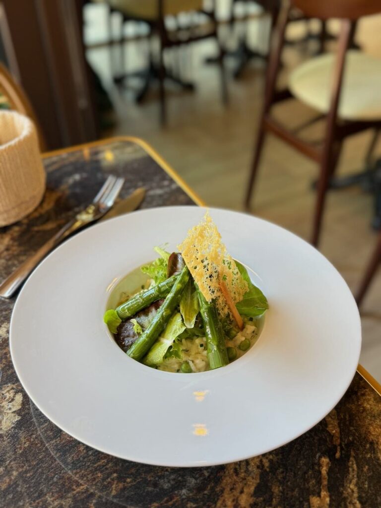Risotto d'asperge verte et tuile de parmesan dans une assiette creuse blanche
