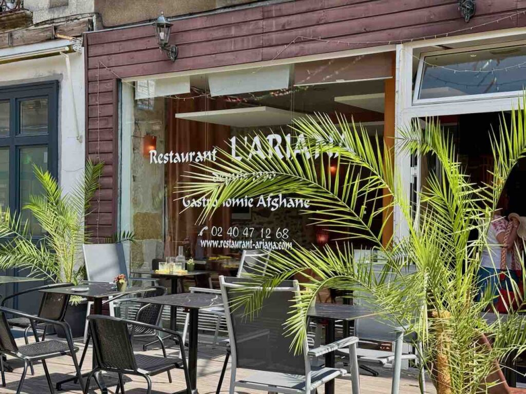 Devanture du restaurant l'Ariana avec terrasse et plantes vertes