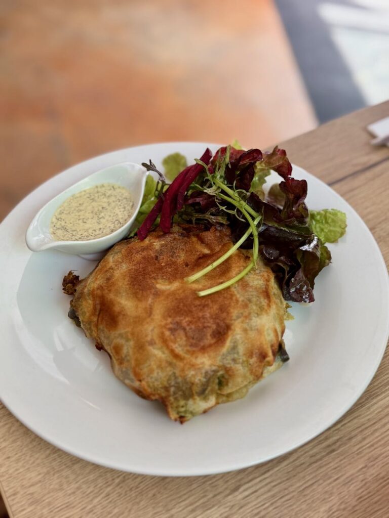 Pastilla, salade et sauce dans une large assiette blanche