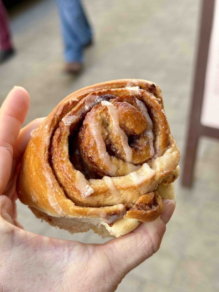 Gros plan sur un cinnamon roll tenu dans la main