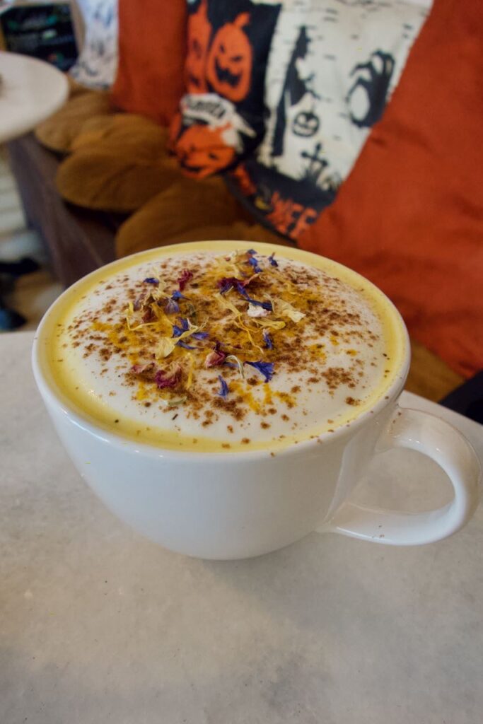 Pumpkin spice latte surmonté d'épices et de fleurs dans une grande tasse blanche