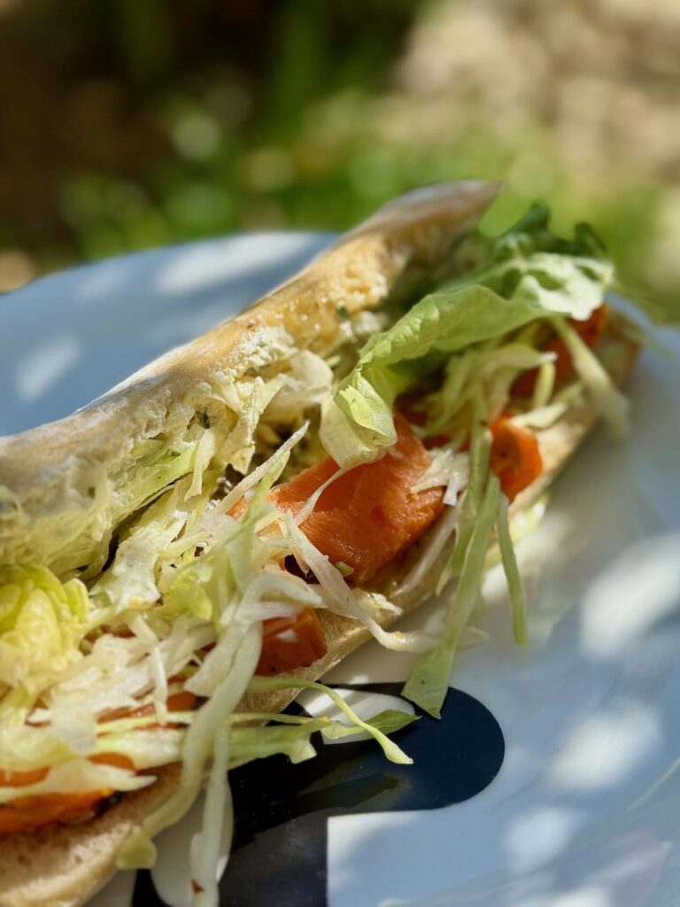 Sandwich patate douce, salade et légumes dans une assiette blanche