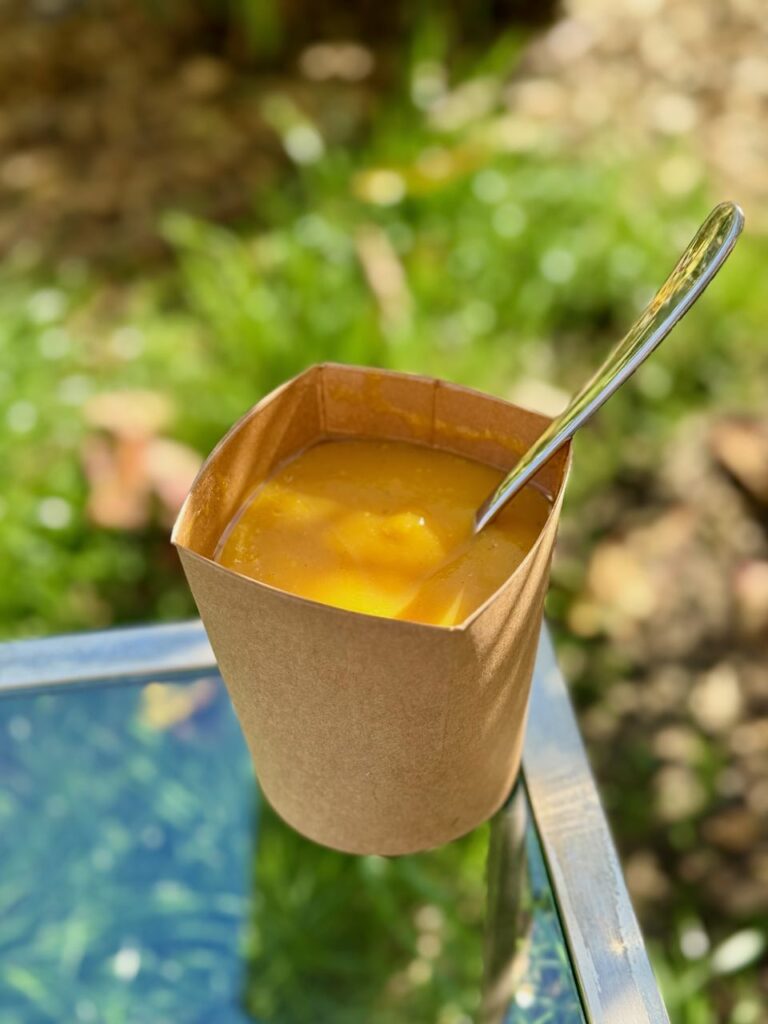 Soupe de courge dans un récipient en carton avec une cuillère en métal dedans