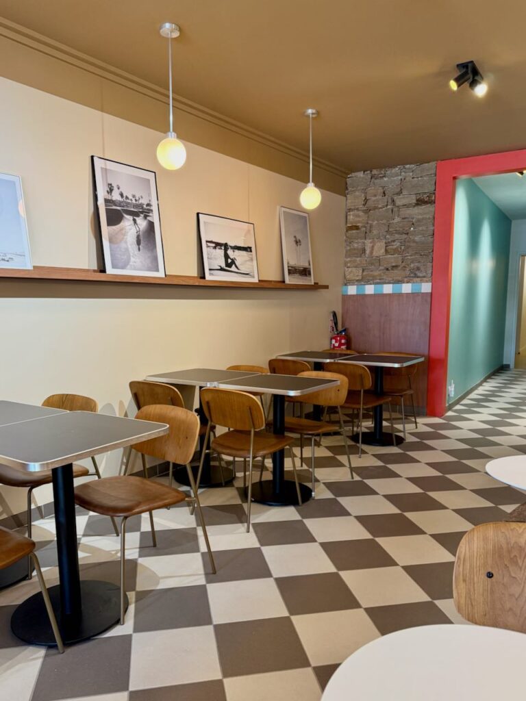 Intérieur de la pizzéria avec sol à carreaux noirs et blancs, tables noires et chaises en bois, photos noir et blanc vintage au mur