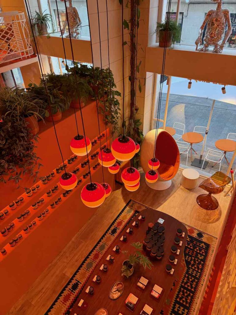 Vue de mezzanine sur des luminaires boules accrochés au bout d'un fil et tombant au dessus de la table sur laquelle sont posés les produits CBD au RDC