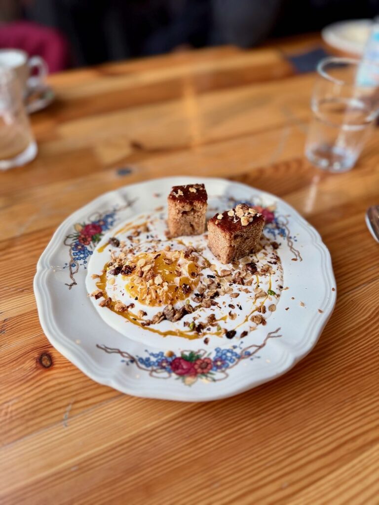 Tranche de clémentine dans de la crème de coco accompagnée de deux morceaux de pain d'épices dans une assiette creuse vintage à fleurs
