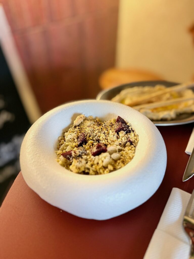 Crumble salé dans une assiette ronde, creuse et à bords très hauts, blanche avec aspérités