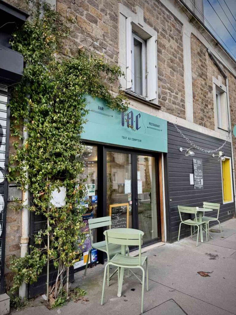 Devanture du restaurant vitrée avec une plante grimpante feuillue sur la gauche