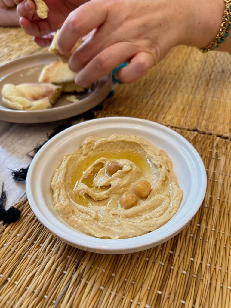 Houmous dans un bol blanc avec des pois chiches sur le dessus