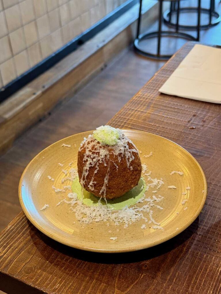 Arancini surmonté de parmesan râpé dans une assiette en grès jaune