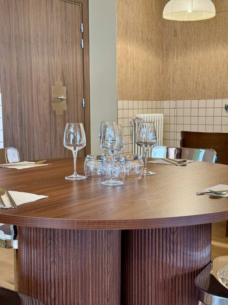 Table en bois ronde design, chaises en aluminium et verres transparents