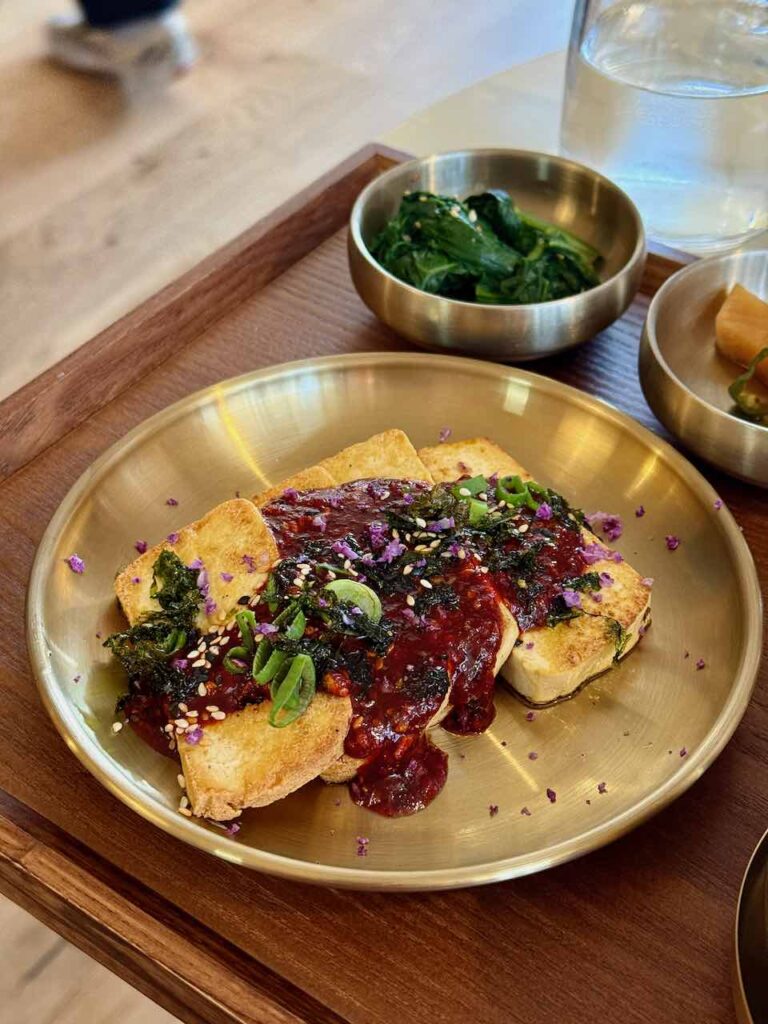 Tofu frit en tranche avec sauce pimentée dans une assiette ronde en métal doré