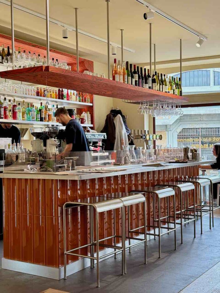 Zinc en faïence rouge, tabourets design en métal, nombreuses bouteilles au comptoir