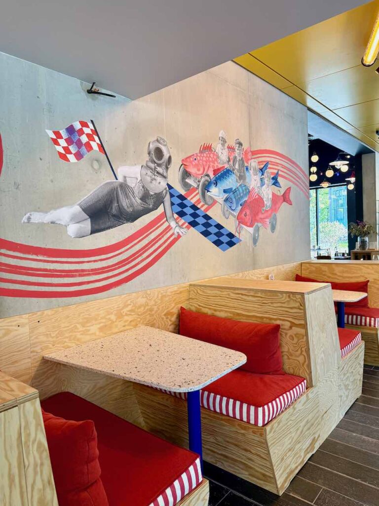 Alcôve avec banquettes en bois et coussins rouges, mur béton illustré