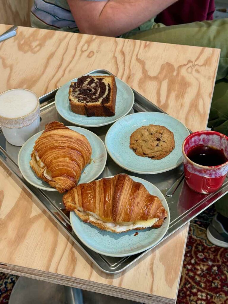 Deux croissants, un cookie, un marbré, un chaï et un filtre sur un plateau en fer