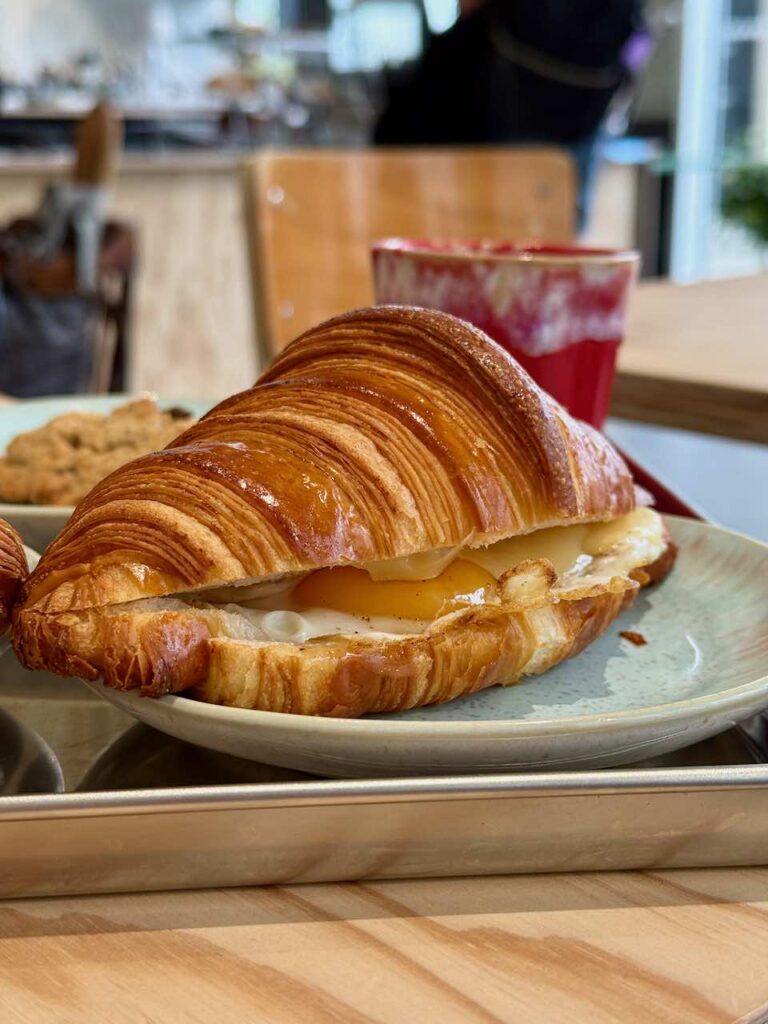 Croissant garni de fromage avec un oeuf au plat dans une assiette en grès bleu gris