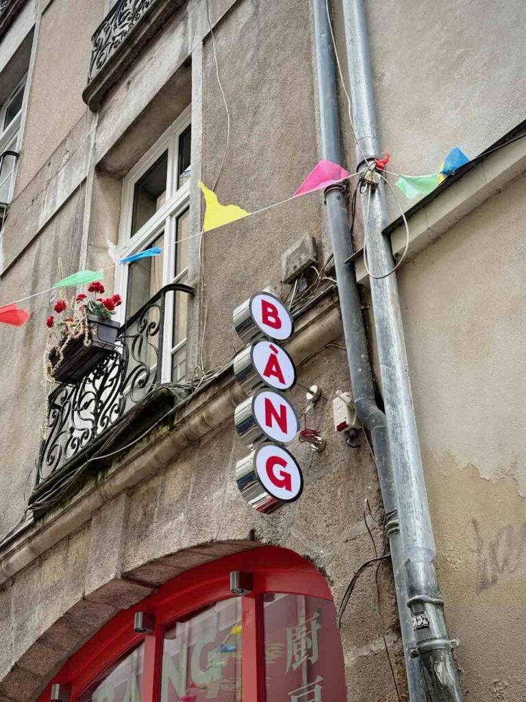 Enseigne de Bang Bang indiquant "Bang" grâce à trois lettres rondes rouges sur blanc