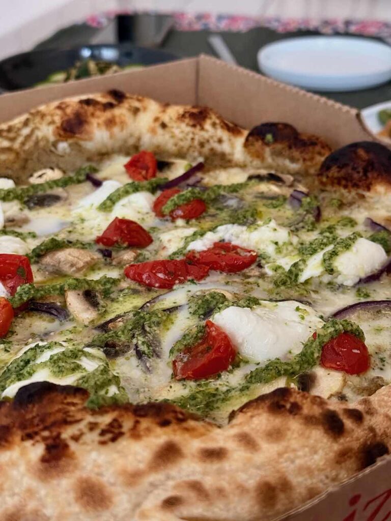 Gros plan sur une pizza surmontée de tomates cerises, mozza, oignons