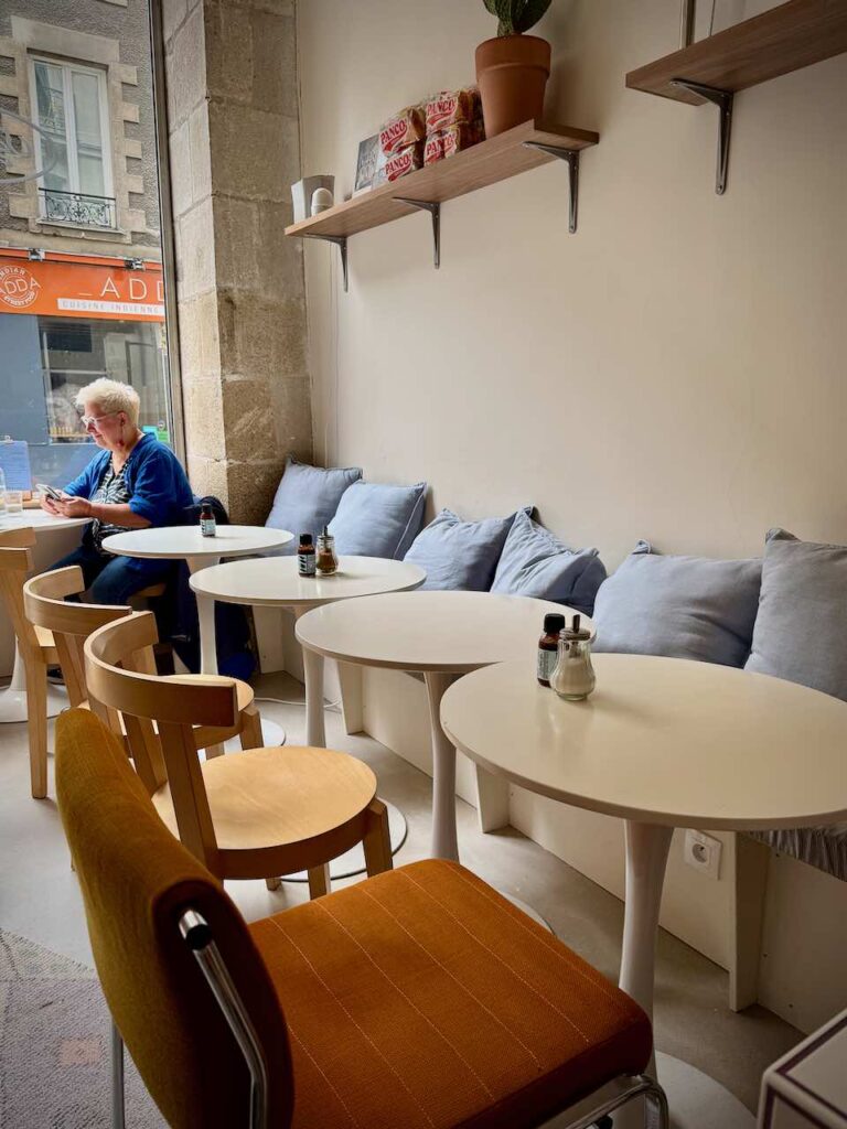 Tables rondes blanches et chaises en bois, banquette avec coussins