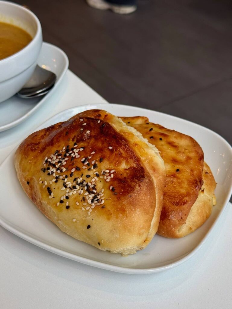 Deux pains bien dorés parsemés de sésame noir et blanc dans une assiette blanche