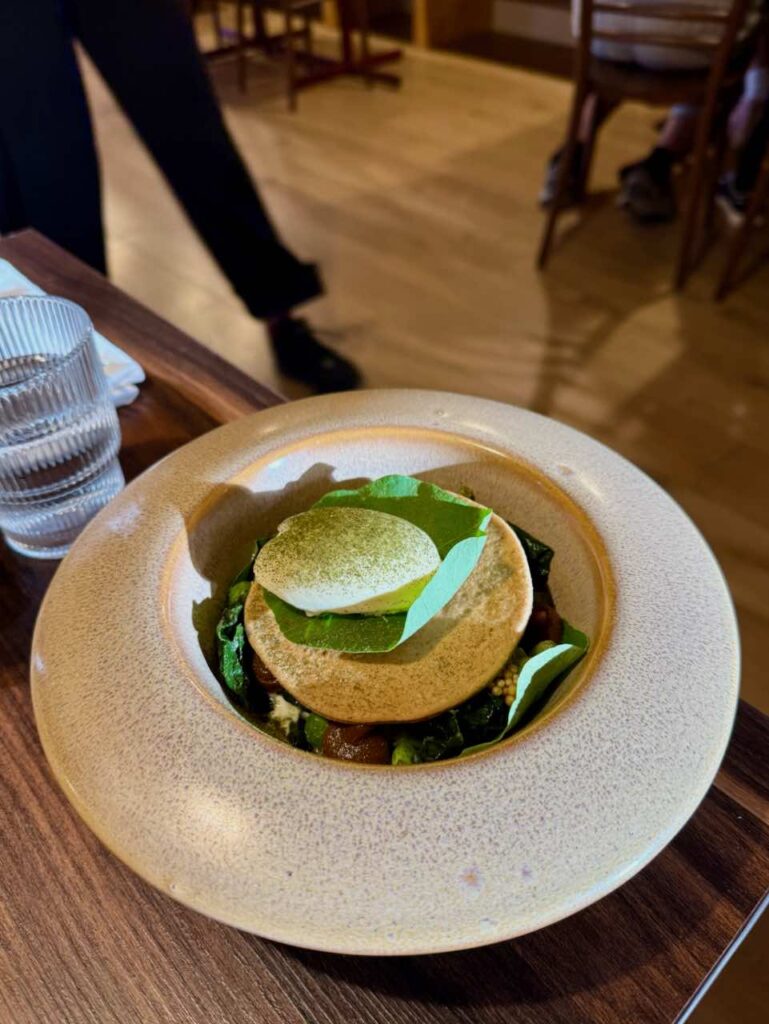 Boule de glace sur une feuille posées sur une biscuit rond, le tout dans une assiette creuse
