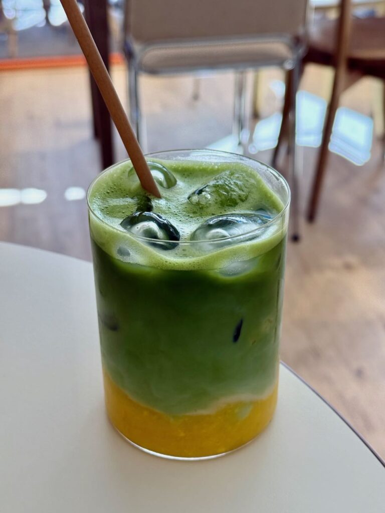 Matcha latte, glaçon et purée de mangue dans un verre transparent avec une paille