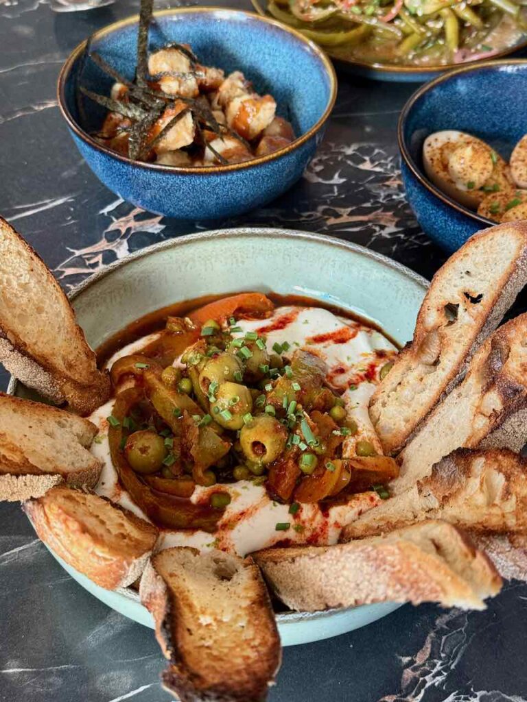 Labneh surmonté d'olives avec tranches de pains toastées dans un bol