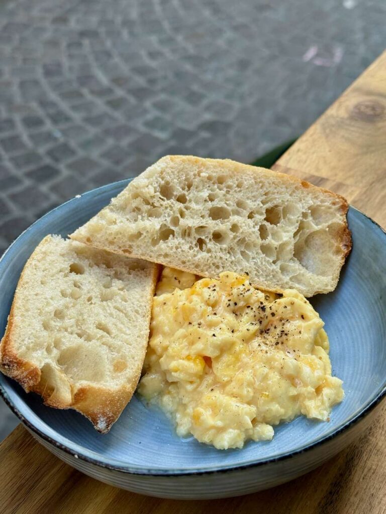 Oeufs brouillés et demi tranches de pain dans une assiette creuse bleue