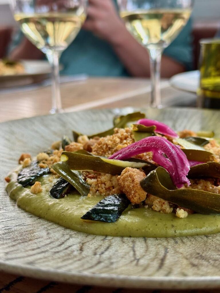 Courgettes tranches et lamelles, pickles roses, crumble dans une assiette grise
