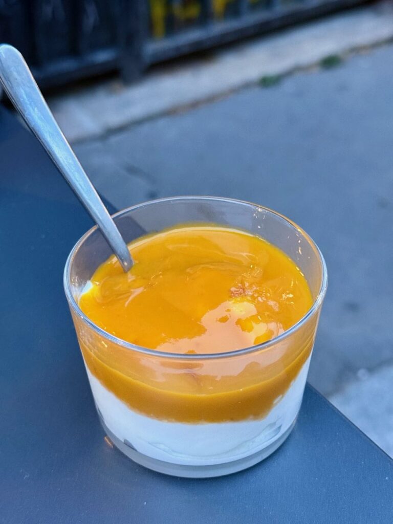 Fromage blanc surmonté d'une purée de mangue dans une verrine avec cuillère