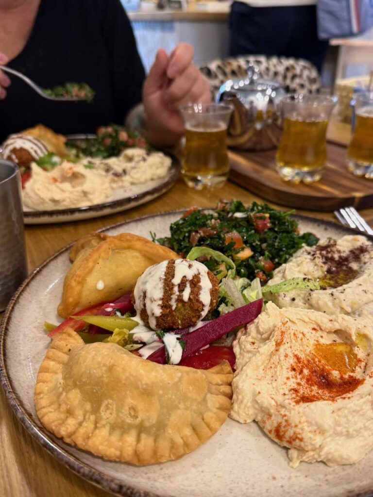 Assiette de mezzes avec des chaussons à gauche, des préparations crémeuses à droite et un falafel au centre