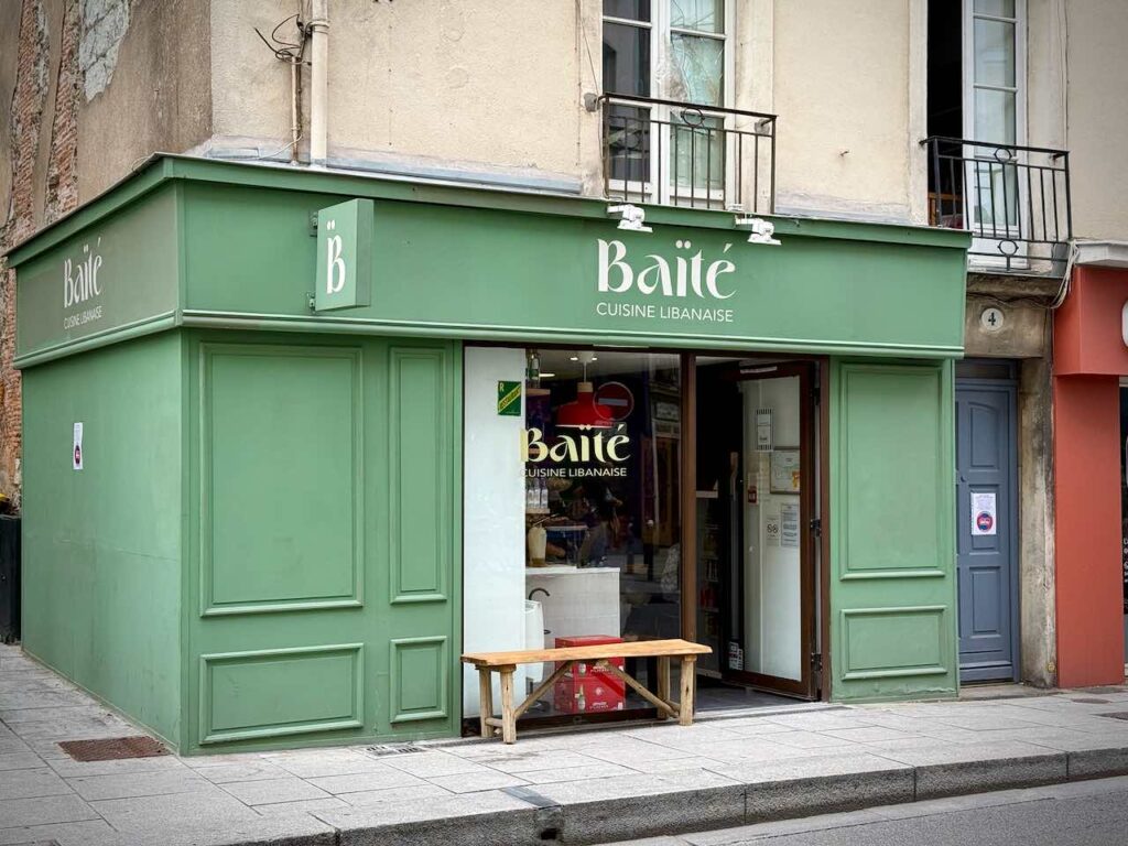Devanture verte de Baïté, un petit banc en bois devant la vitrine
