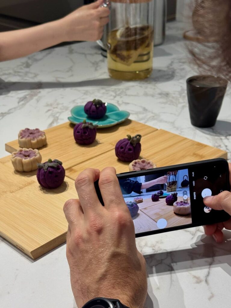 Personne prenant en photo des wagashi une une planche en bois